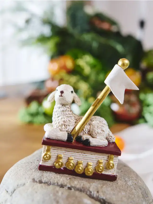 Statuina pasquale con agnello e bandierina su un libro - panna